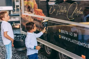 Kind aan het raam van de winkel van De Plaetse Molen