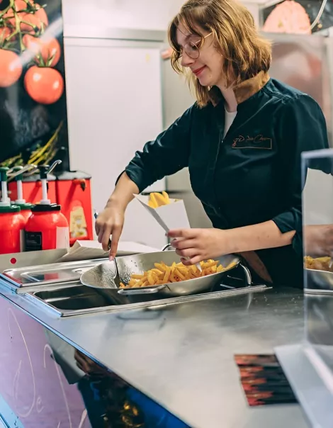 Medewerkster schept verse frietjes op in de mobiele frituur